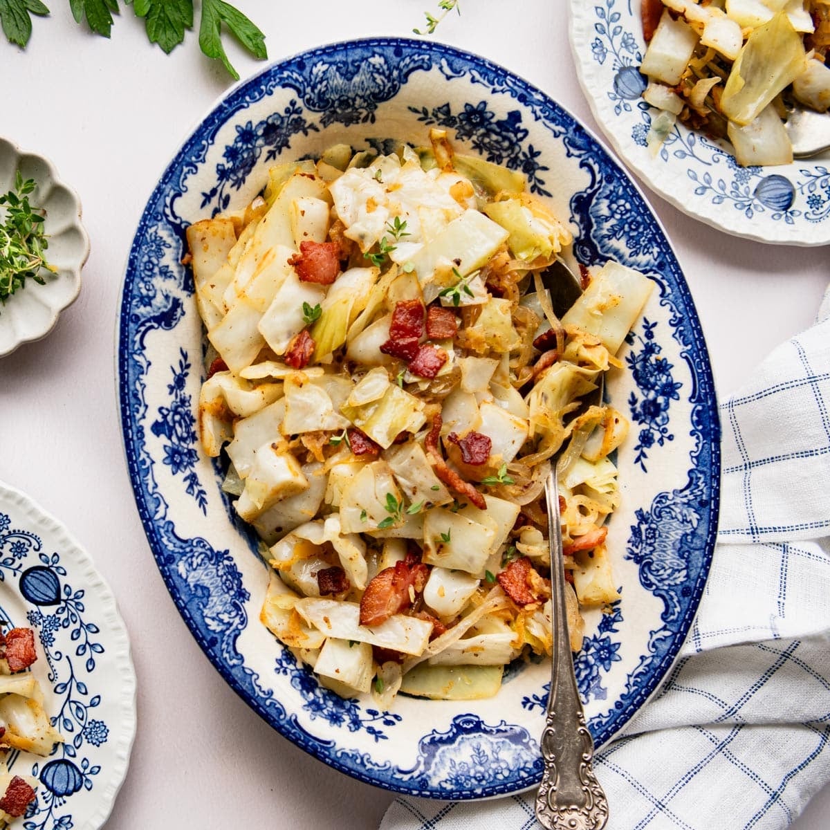 Square overhead shot of Southern fried cabbage with apples and bacon in a blue and white oval bowl.