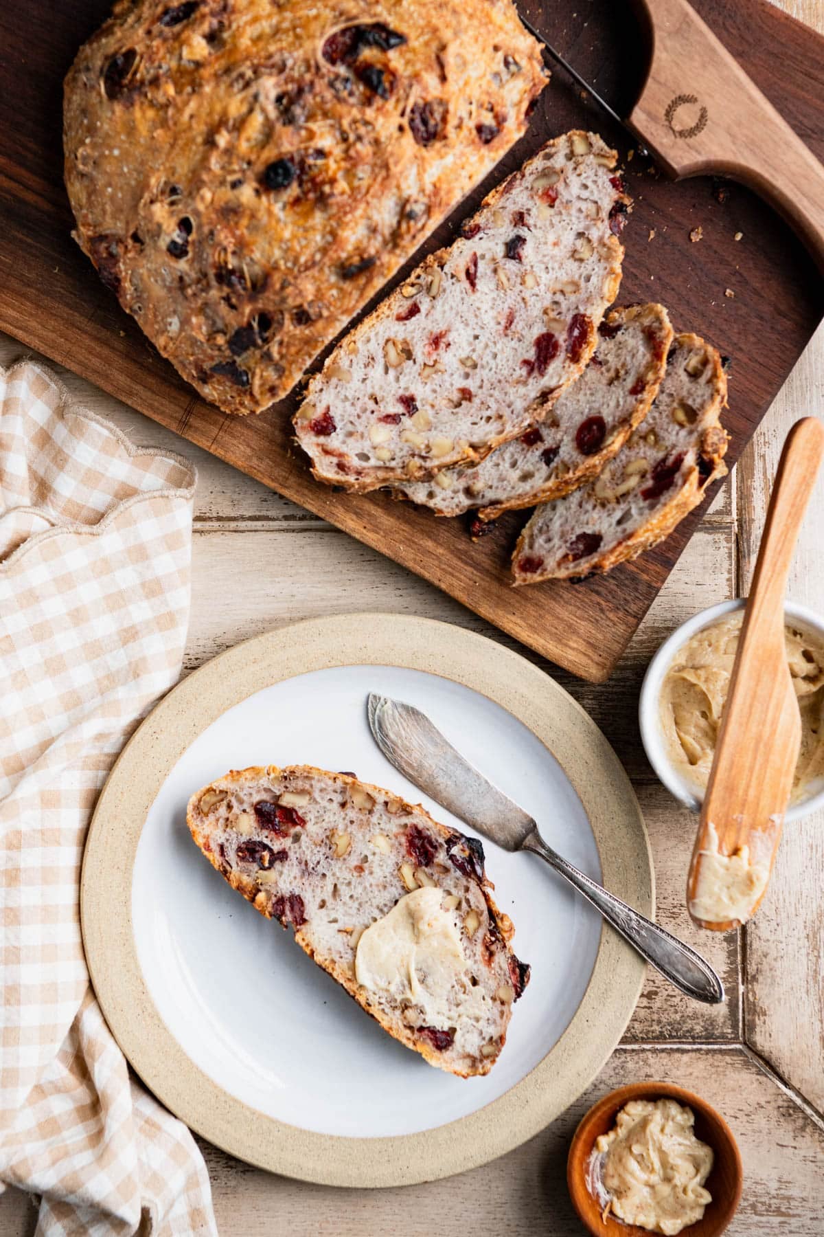 Overhead shot of a sliced loaf of no knead cranberry walnut bread on a table.