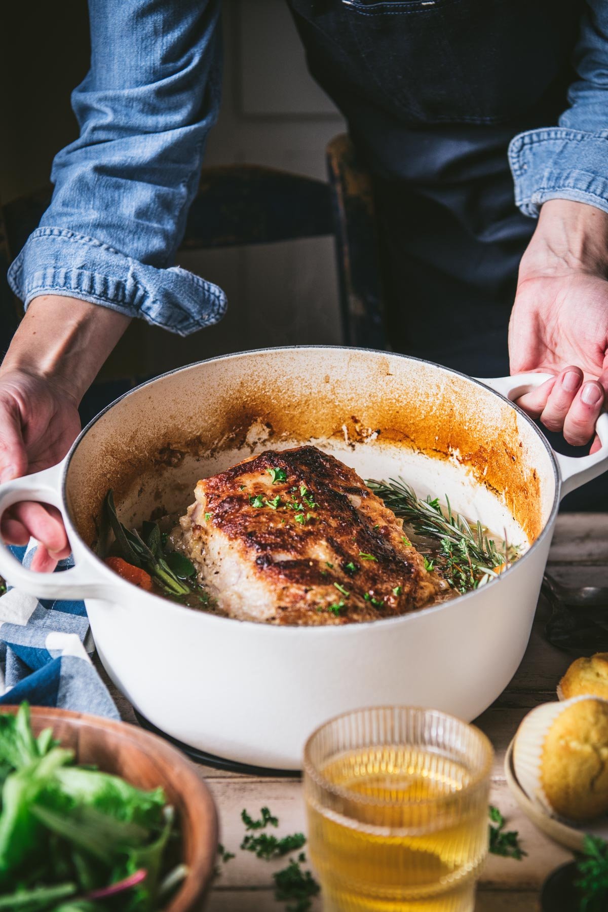 Hands serving a beer braised pork loin roast in a Dutch oven