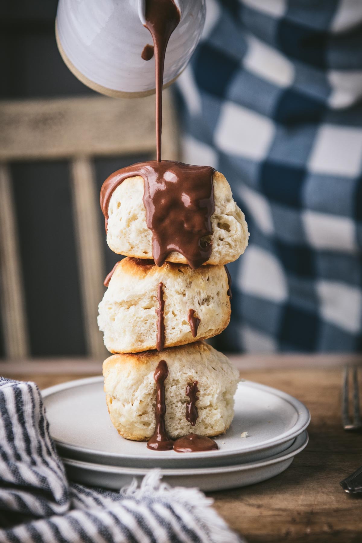 Drizzling chocolate gravy over a stack of biscuits