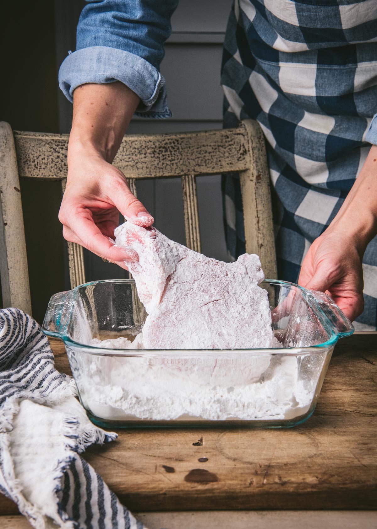 Dredging pork chop in seasoned flour