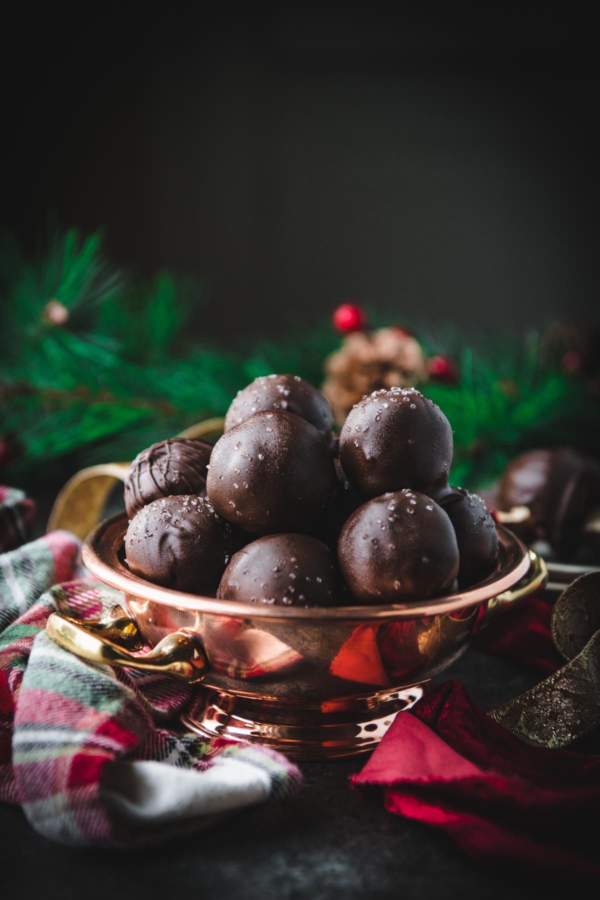 Front shot of a copper bowl full of dark chocolate covered peanut butter balls