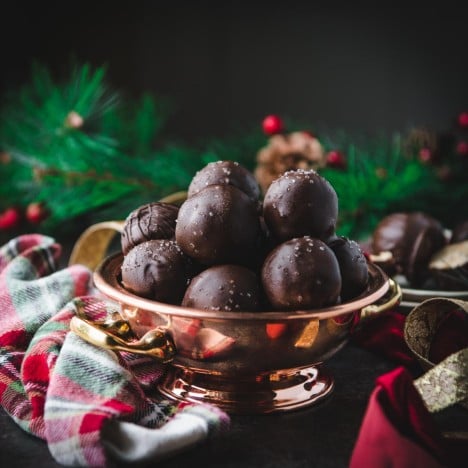 Square side shot of dark chocolate peanut butter balls with sea salt in a copper bowl