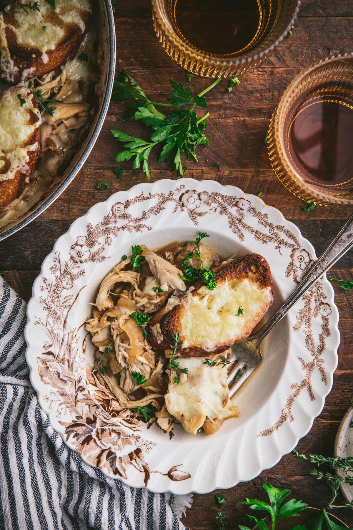Overhead shot of a bowl of french onion chicken bake on a table with a glass of wine