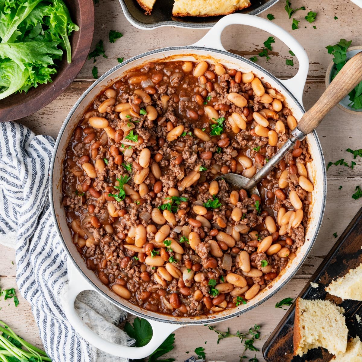 Square overhead image of a beef and baked beans casserole with cornbread on a table