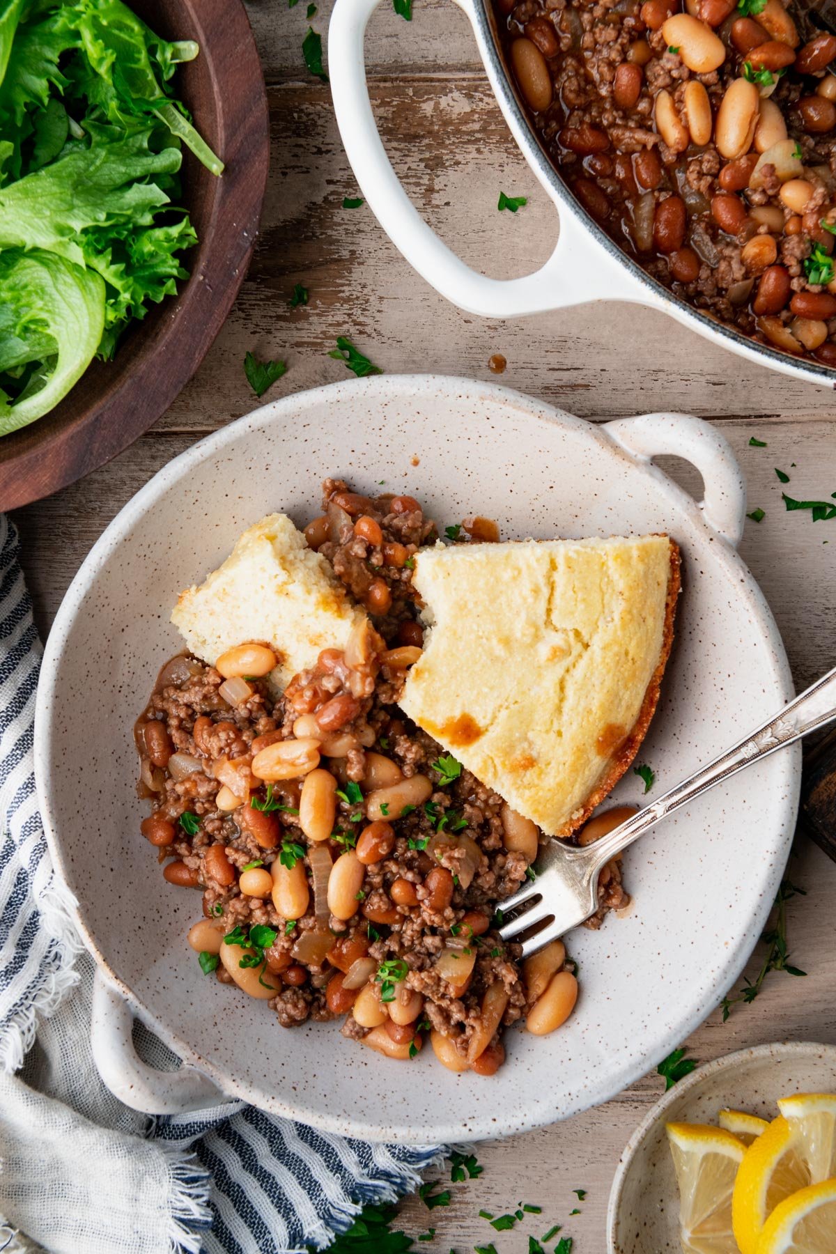 Beef and baked bean casserole in a dish with a side of cornbread