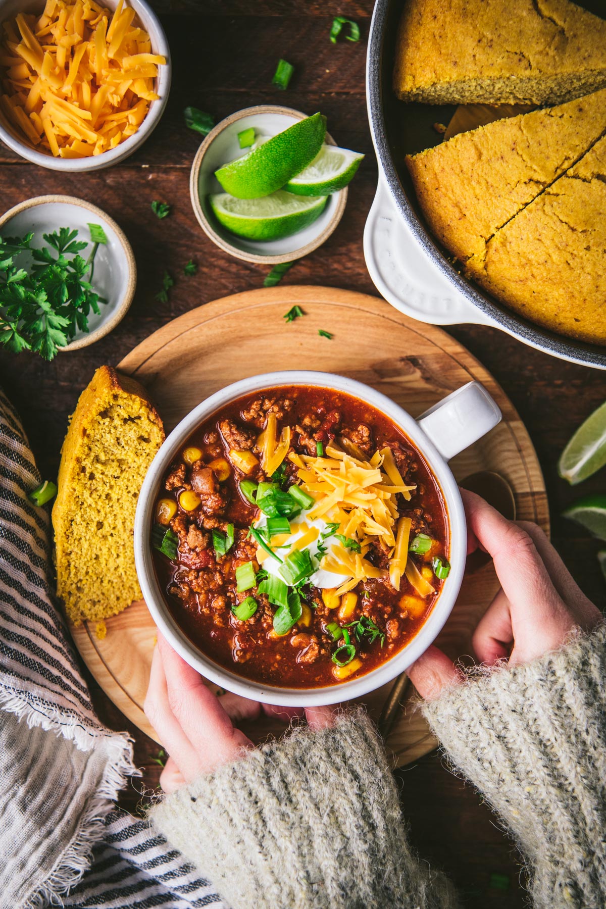 Overhead shot of hands holding a bowl of the best ground turkey chili recipe on a dinner table