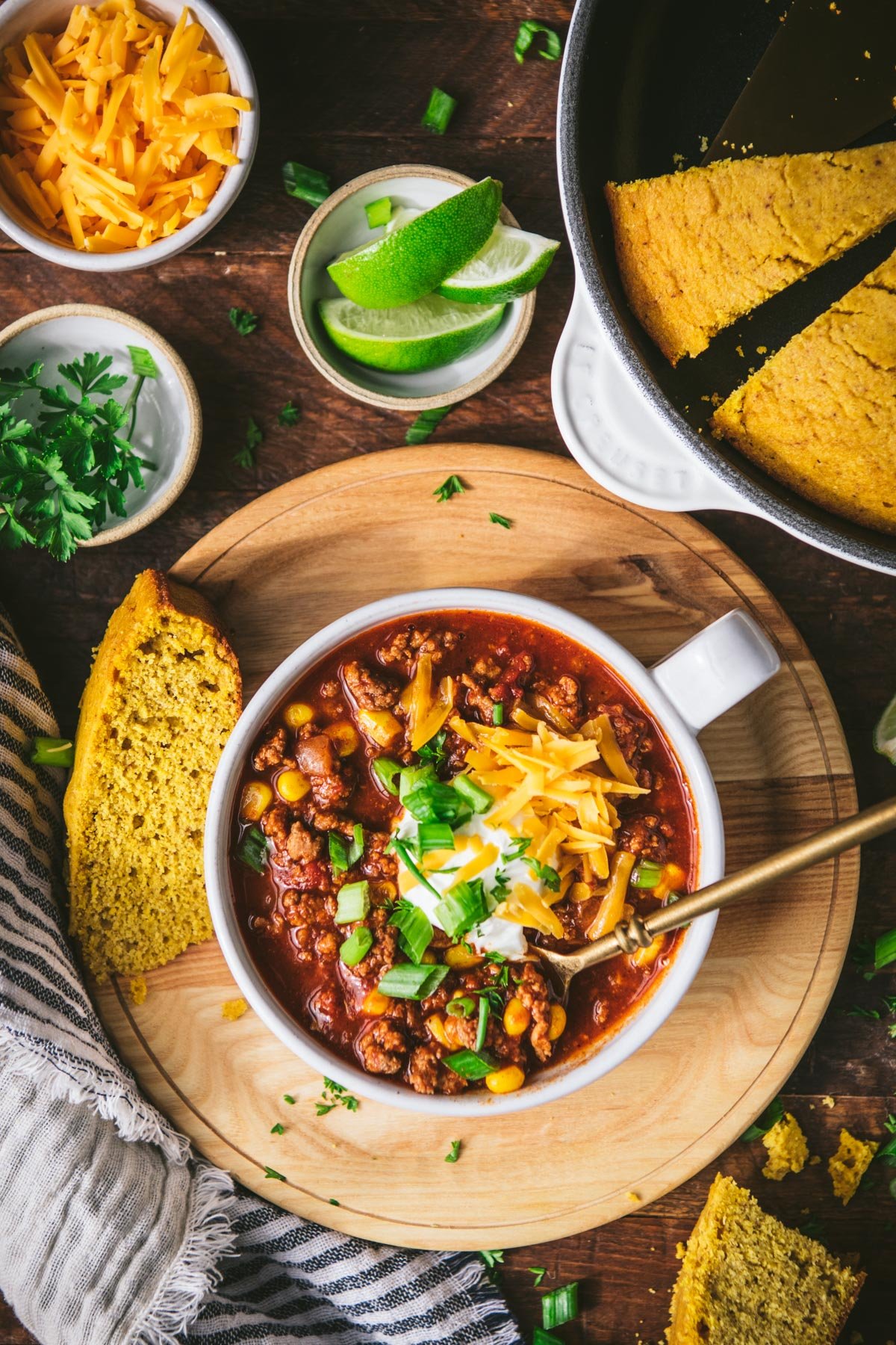 Overhead image of a bowl of ground turkey chili on a table with a side of cornbread
