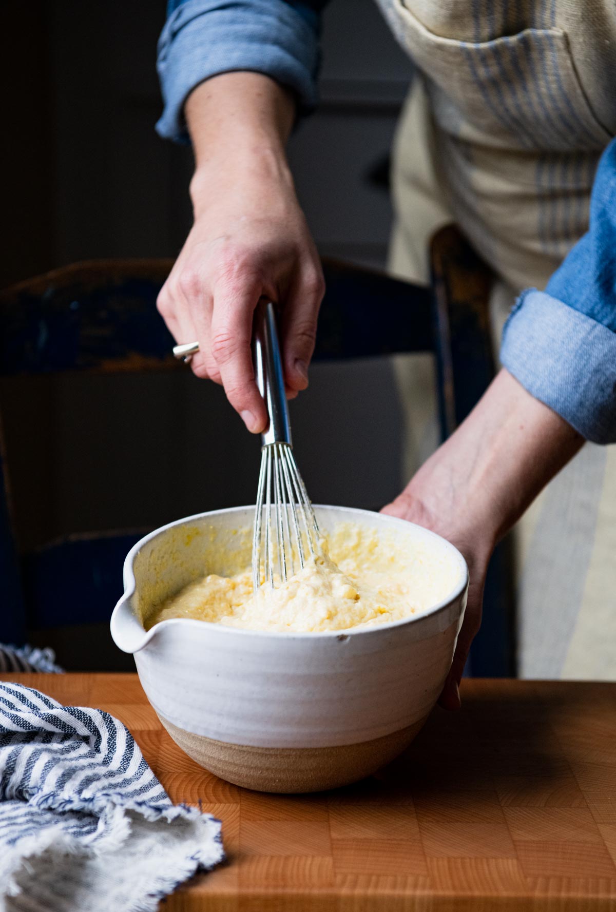 Whisking together cornbread batter in a white bowl