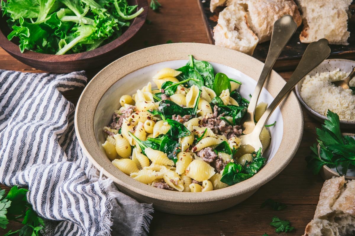 Horizontal side shot of a bowl of pasta with Italian sausage and spinach