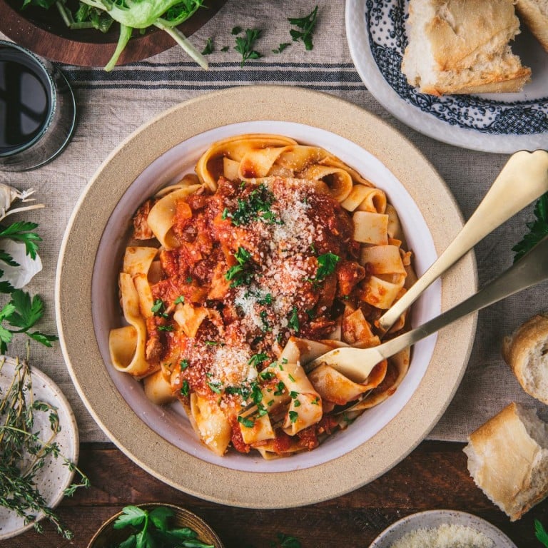 Close overhead shot of pork ragu with pasta in a bowl on a table