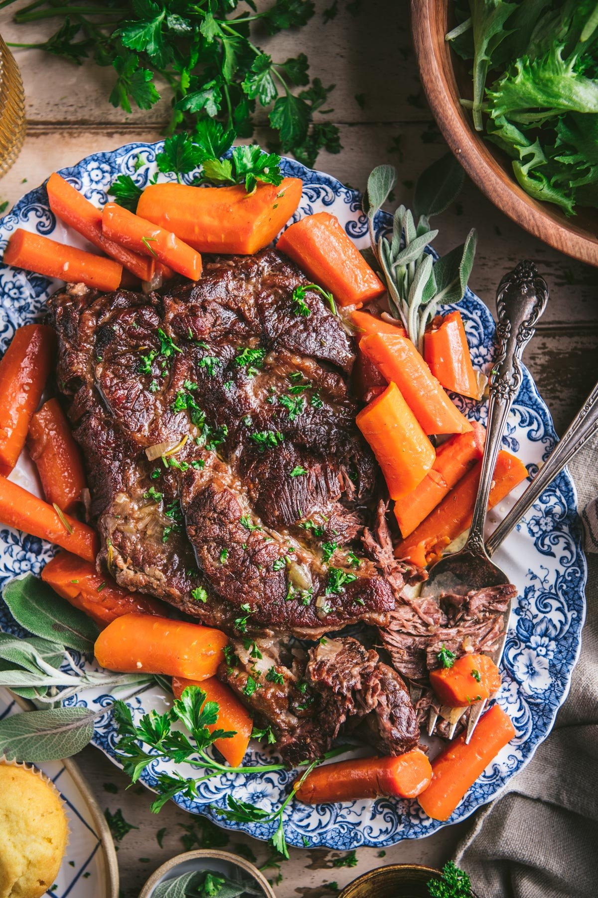 Overhead image of stove top pot roast with red wine and carrots on a blue and white serving tray