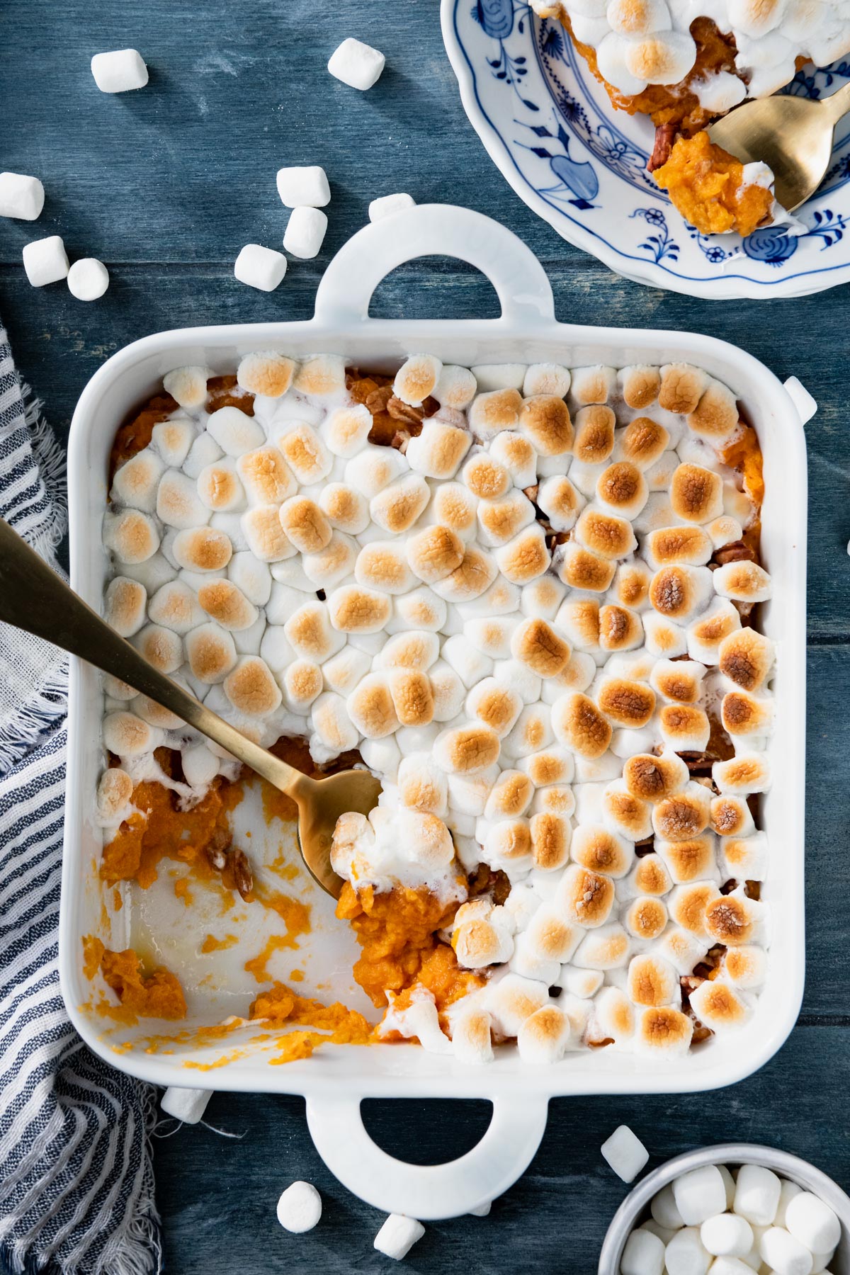 Sweet potato casserole with marshmallows in a white dish on a wooden blue table