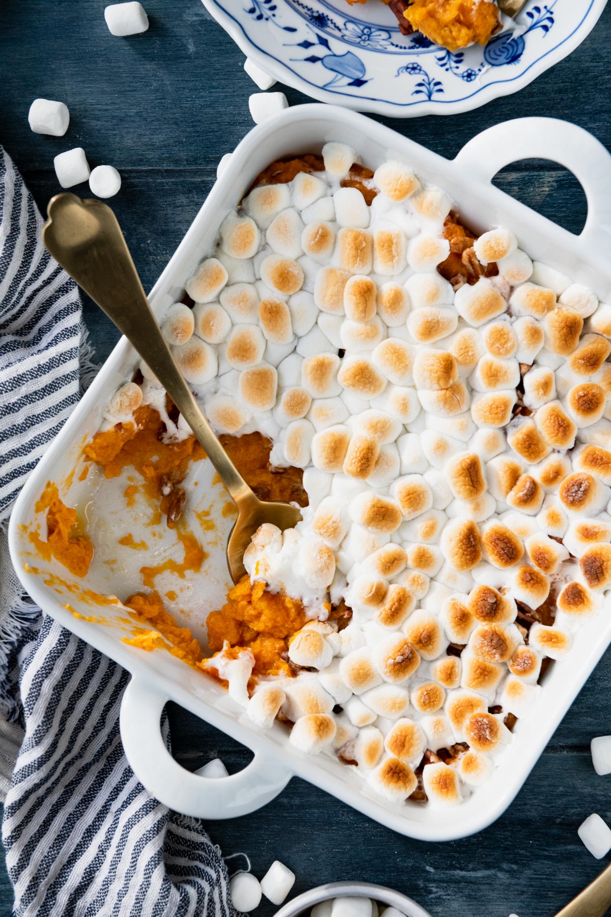 Close overhead shot of a gold spoon in a dish of sweet potato casserole with marshmallows