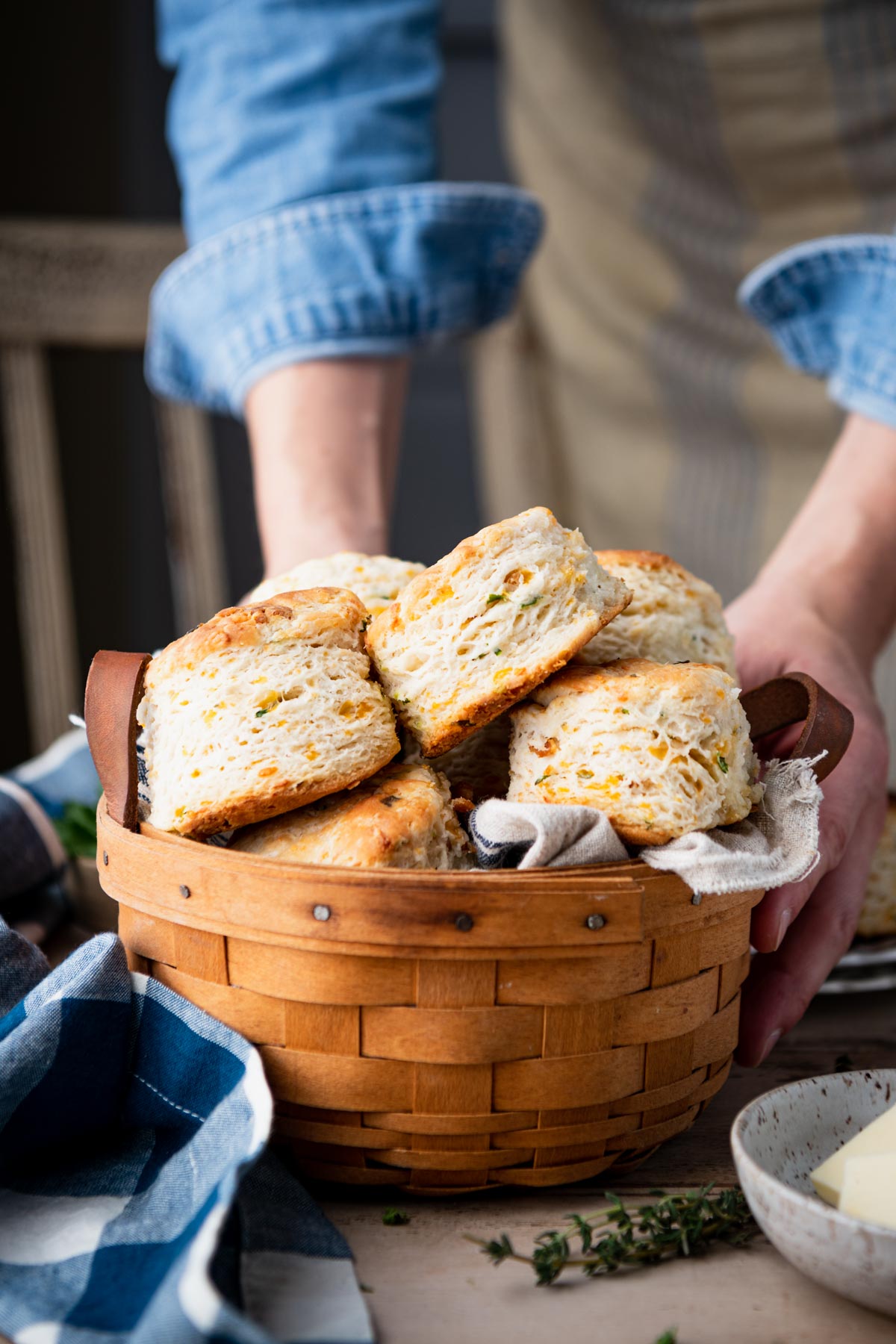 Hands serving a basket of cheddar biscuits with bacon and chives