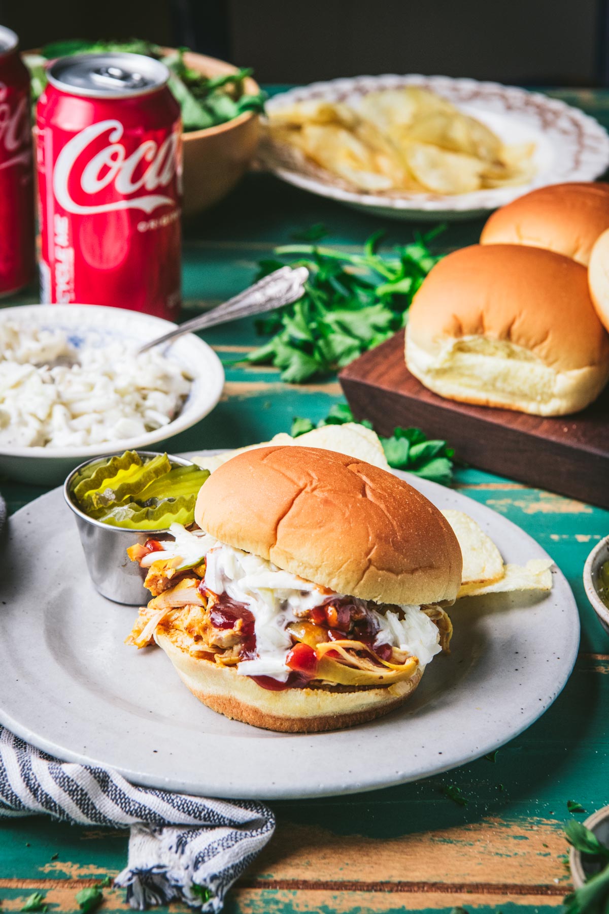 Coca cola chicken sandwich on a plate with sides in the background