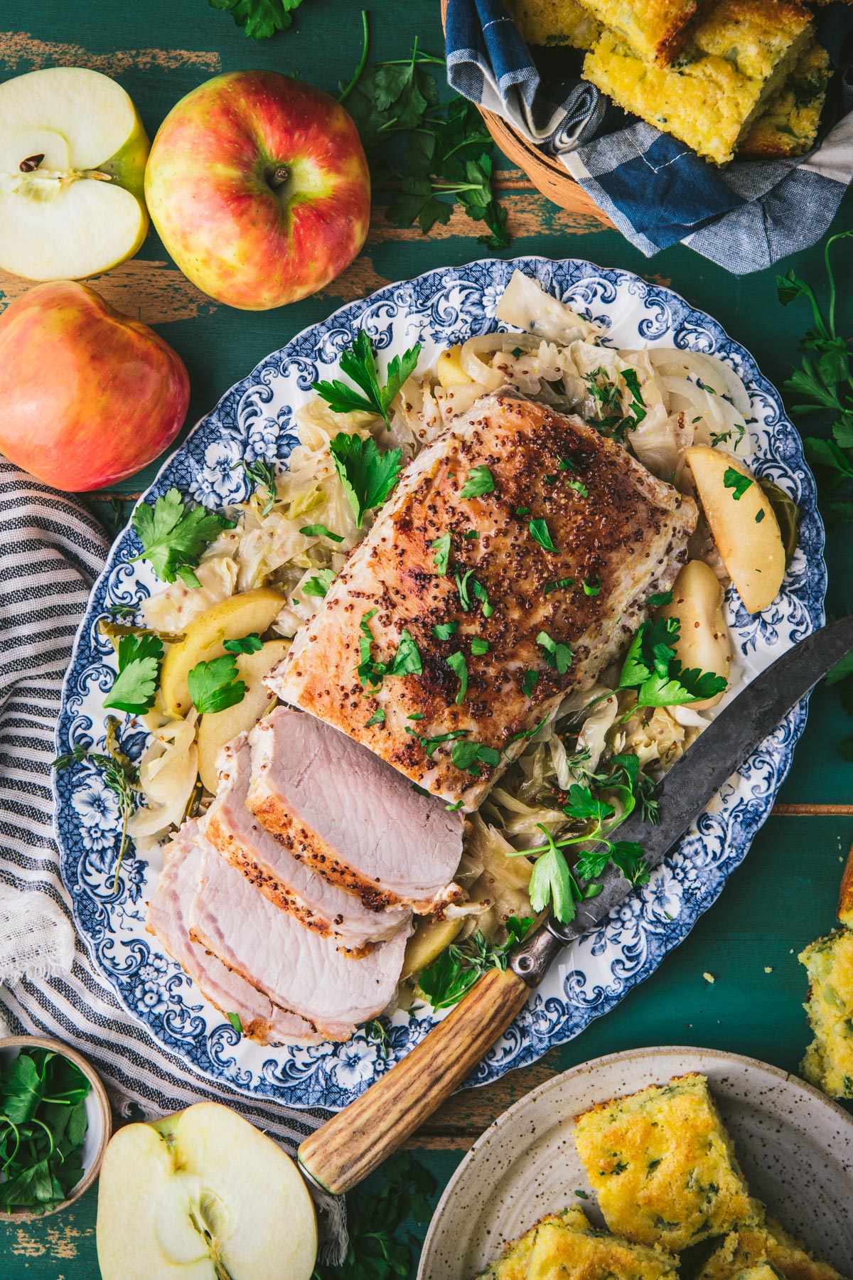 Overhead shot of sliced crock pot pork loin on a platter with cabbage and apples