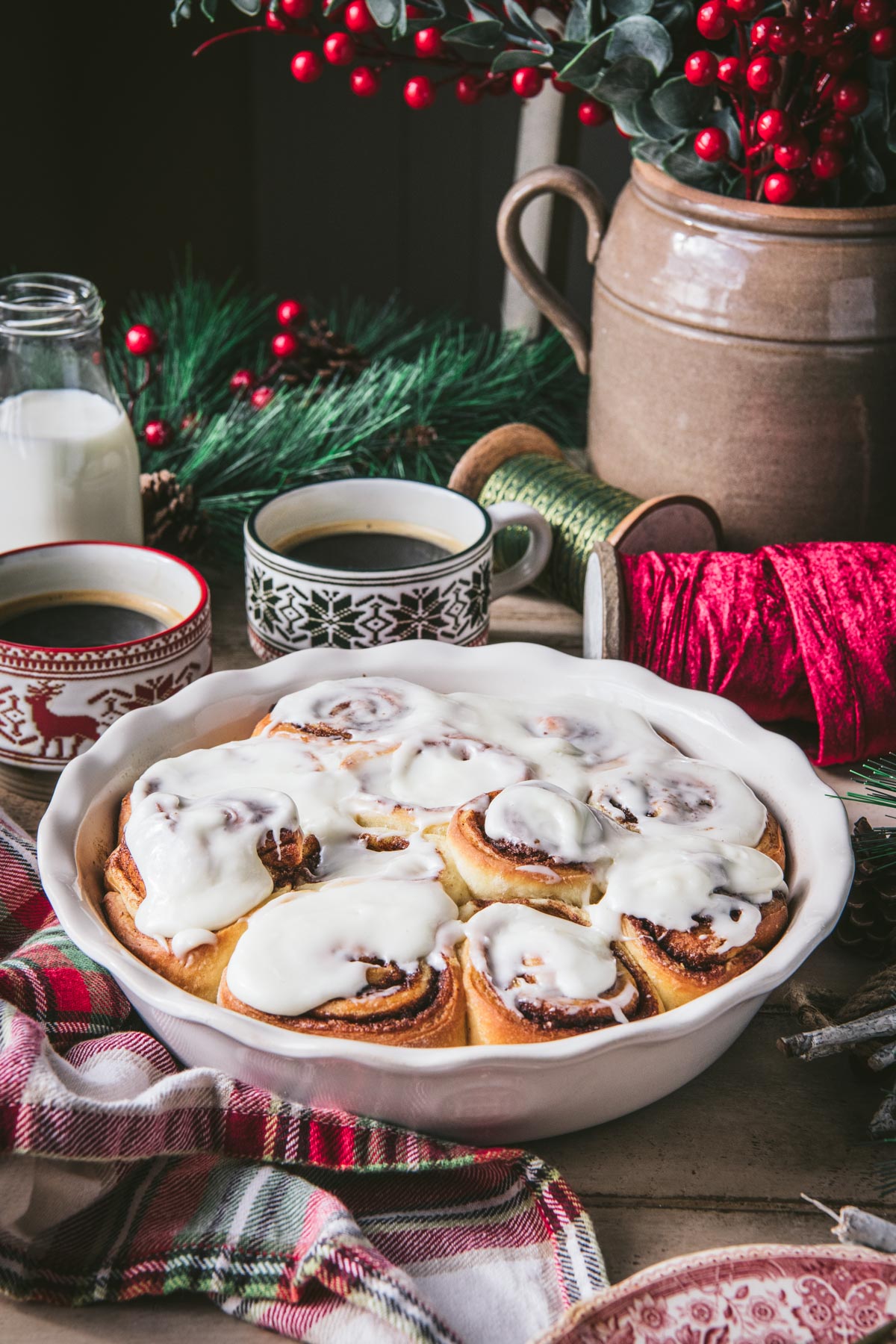 Side shot of a white dish of Christmas cinnamon rolls on a breakfast table