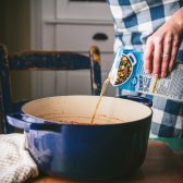 Pouring beef broth into a Dutch oven