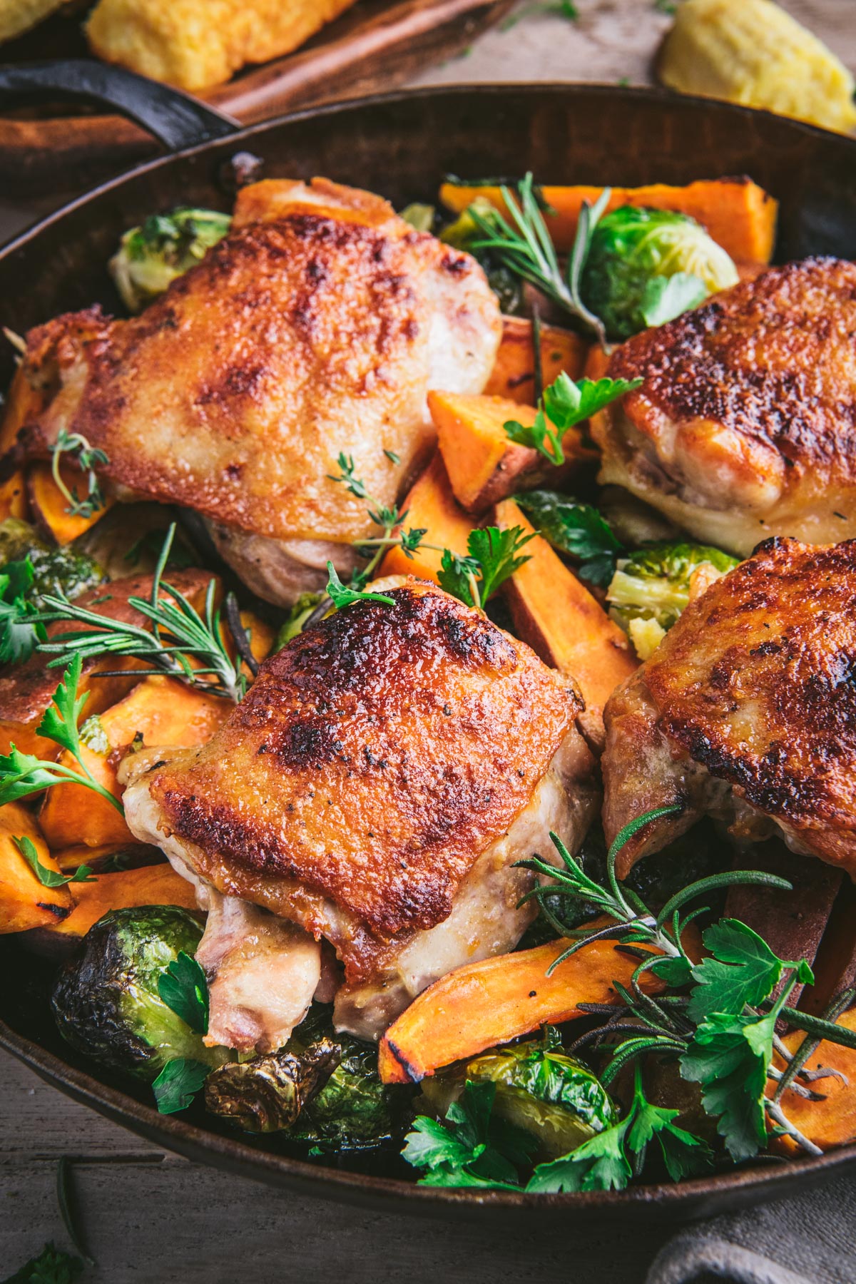 Close up shot of maple roasted chicken thighs and vegetables in a cast iron skillet