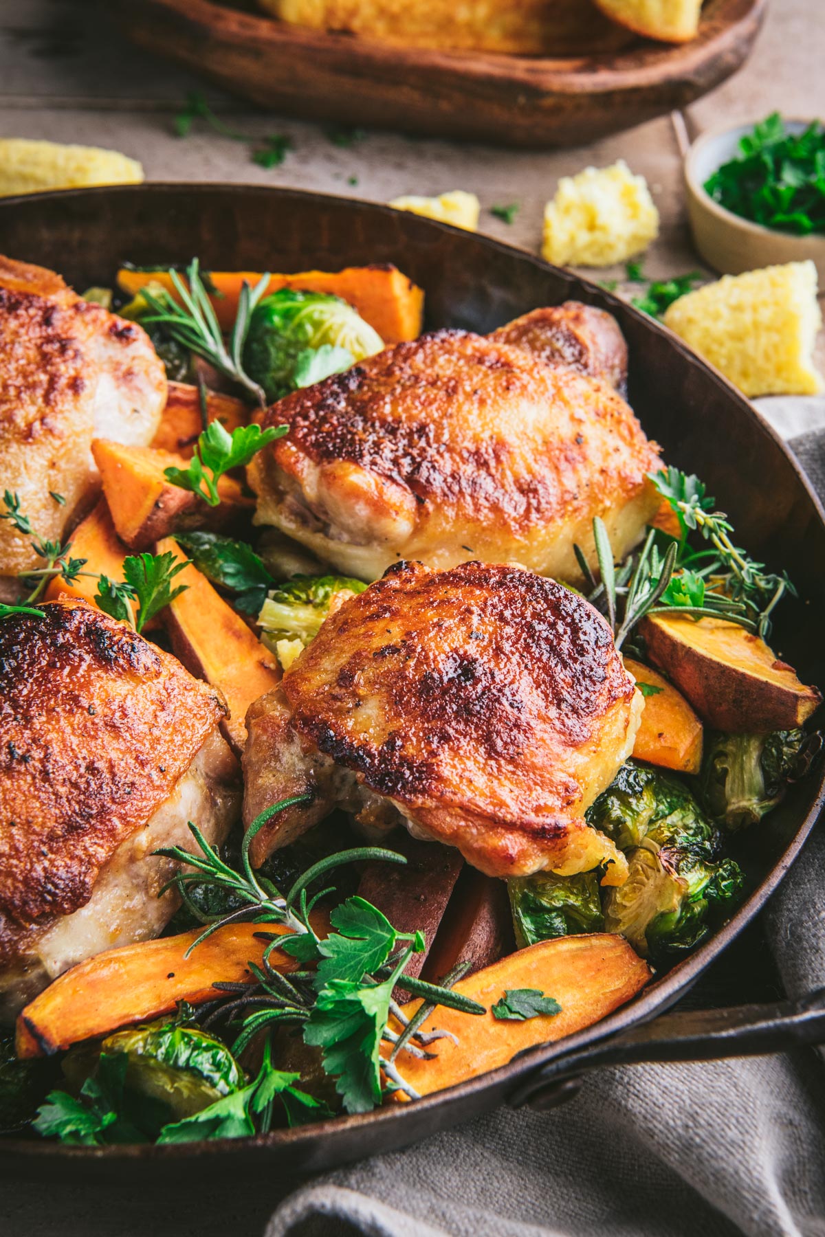 Close up front shot of roasted chicken thighs and vegetables in a cast iron skillet