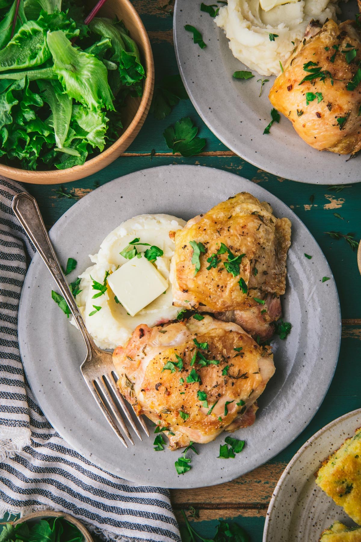 Baked chicken thighs on a plate with mashed potatoes.