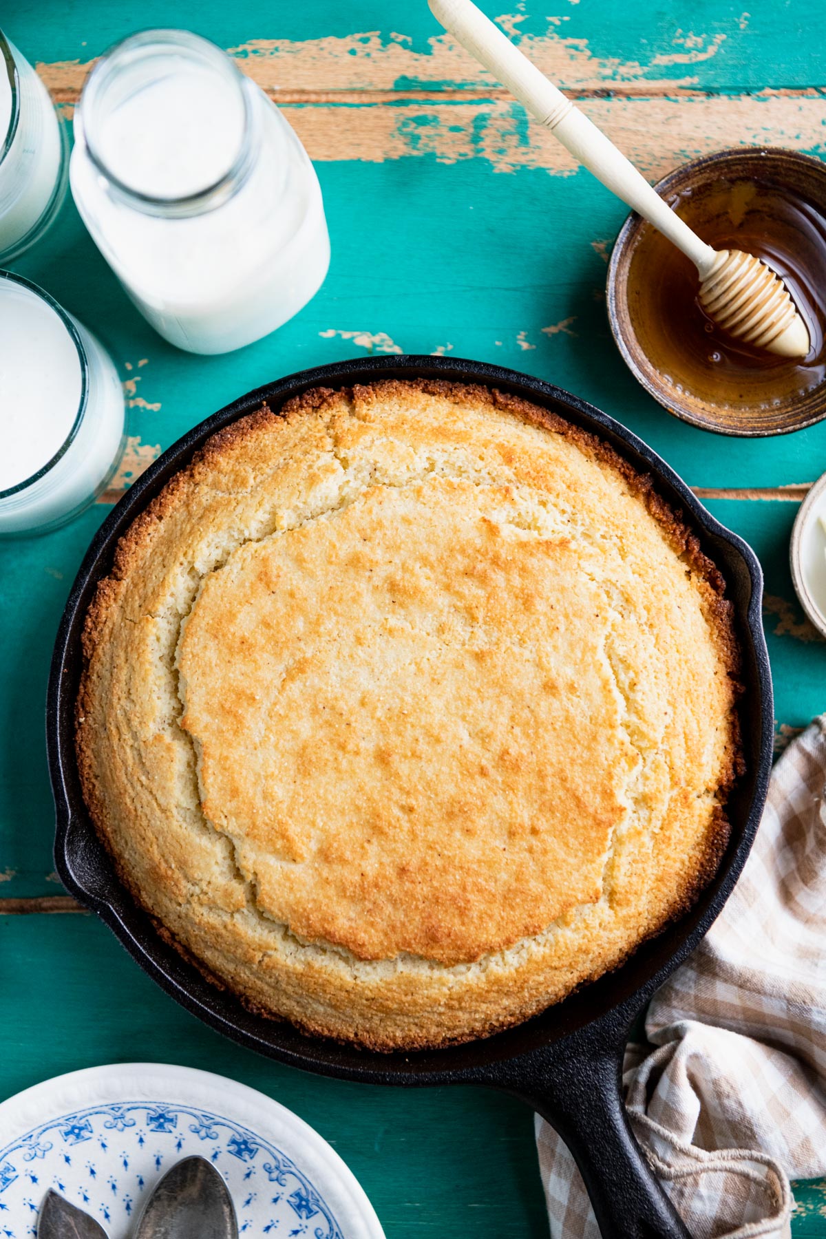 Overhead image of a skillet of Southern cornbread on a rustic turquoise wooden table