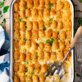 Chicken tater tot casserole on a wooden table with a side salad