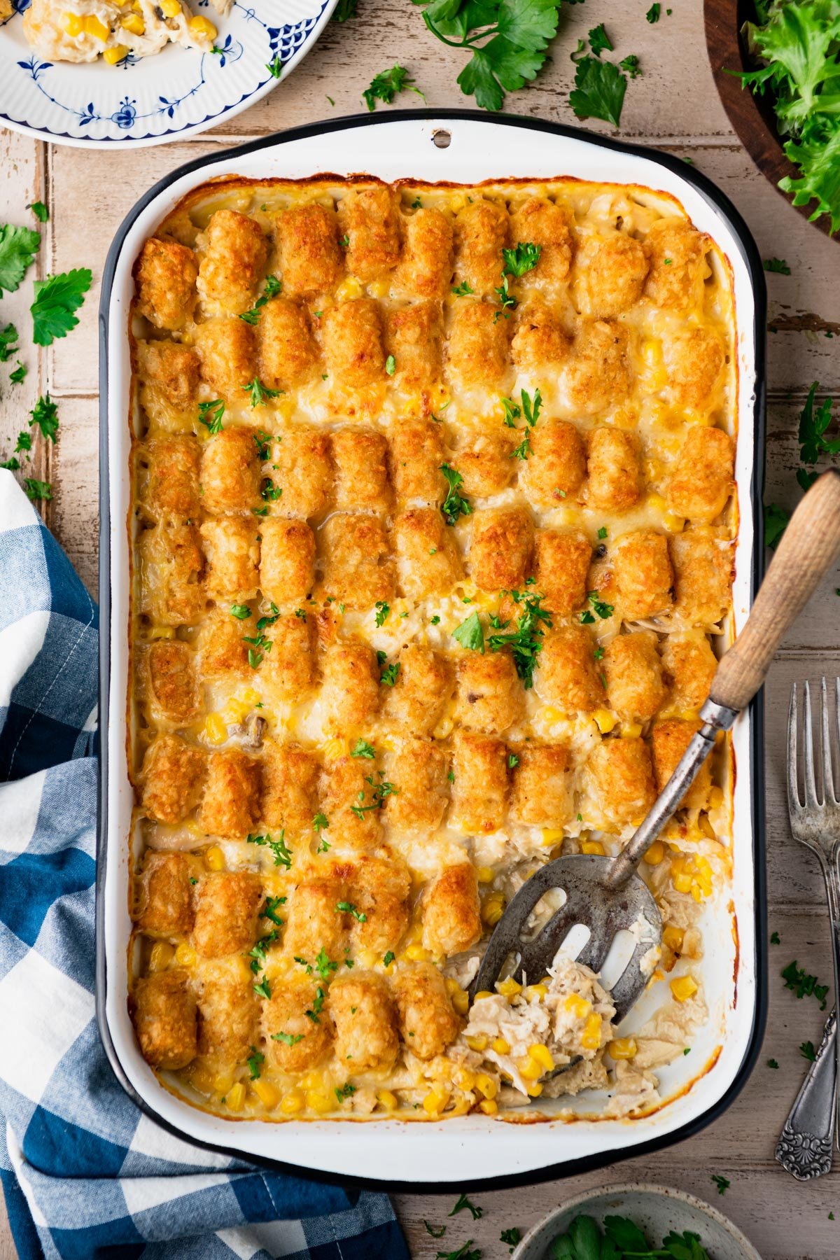 Chicken tater tot casserole on a wooden table with a side salad