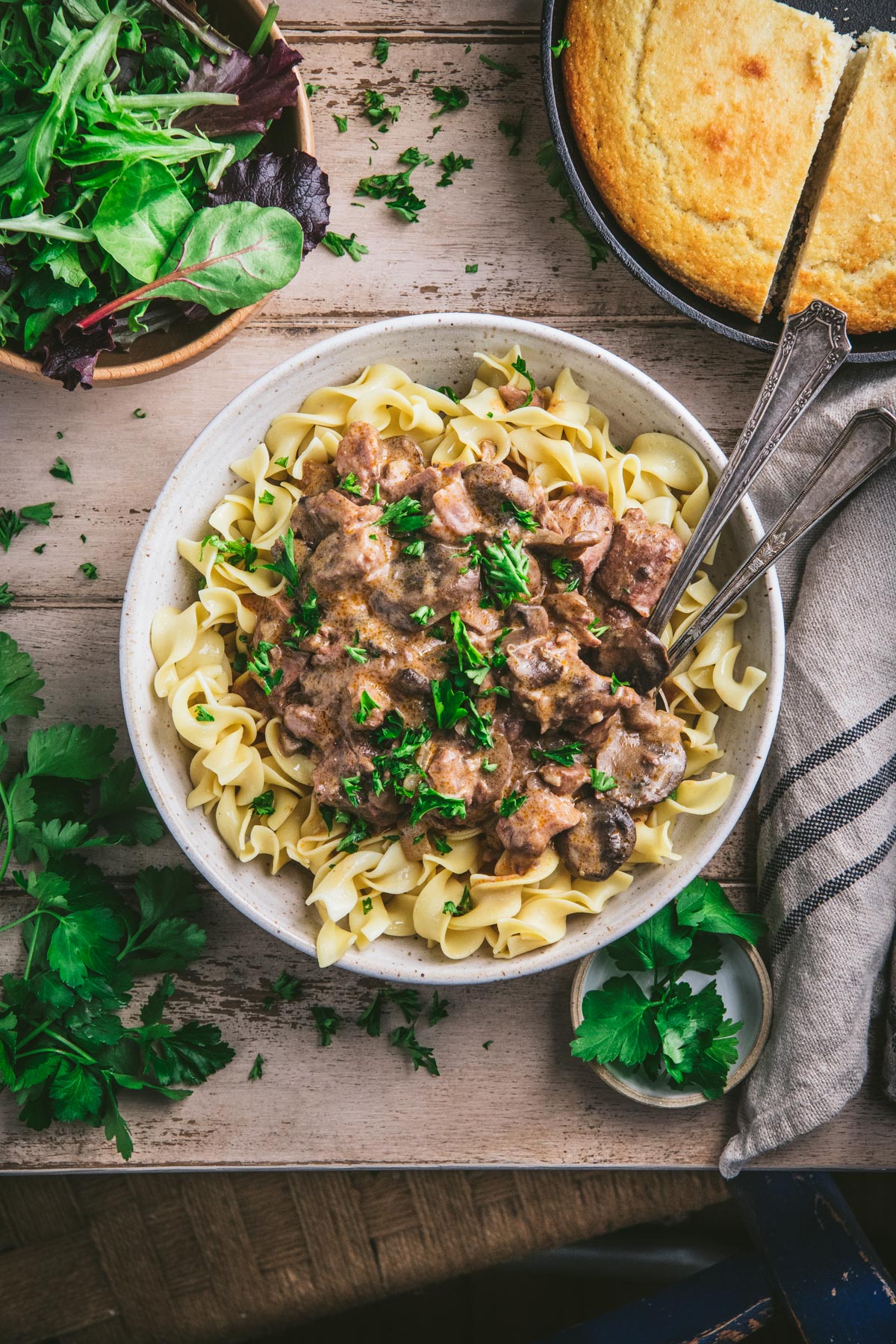Overhead image of easy beef stroganoff in a bowl on a dinner table with a chair next to the table