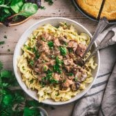 Square overhead image of a bowl of slow cooker beef stroganoff over egg noodles