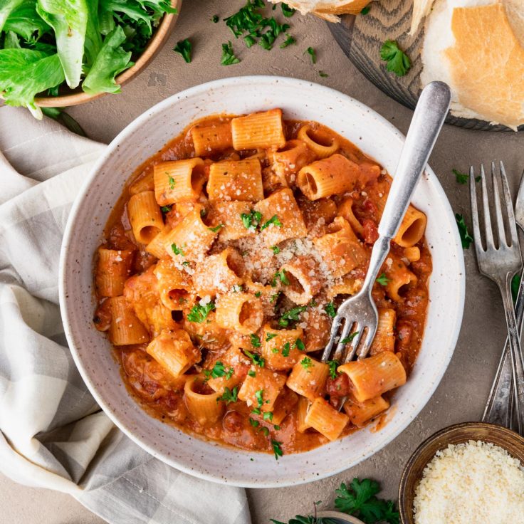 Square overhead image of a bowl of creamy tomato basil pasta