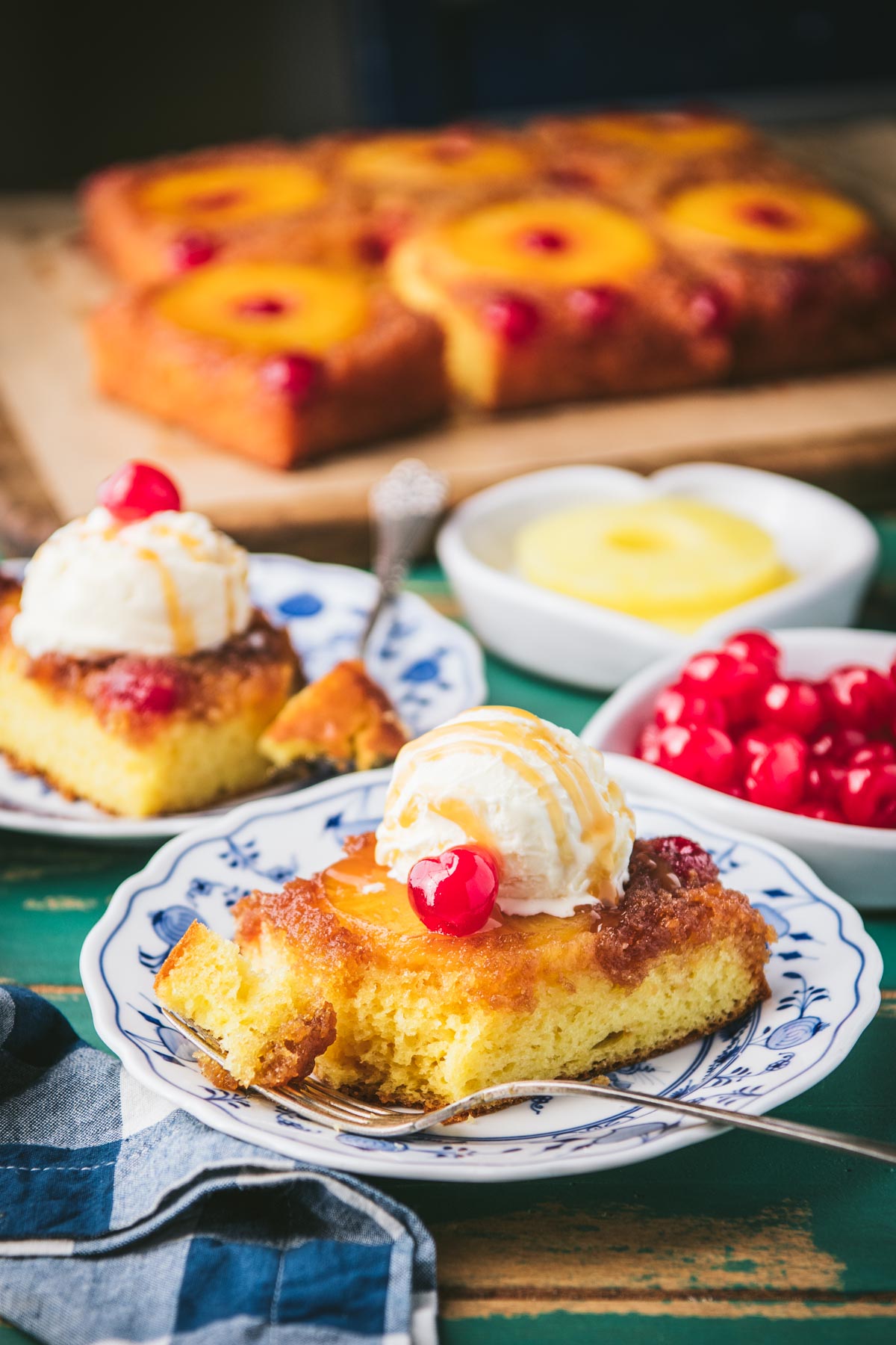 Side shot of two plates of pineapple upside down cake on a rustic wooden table