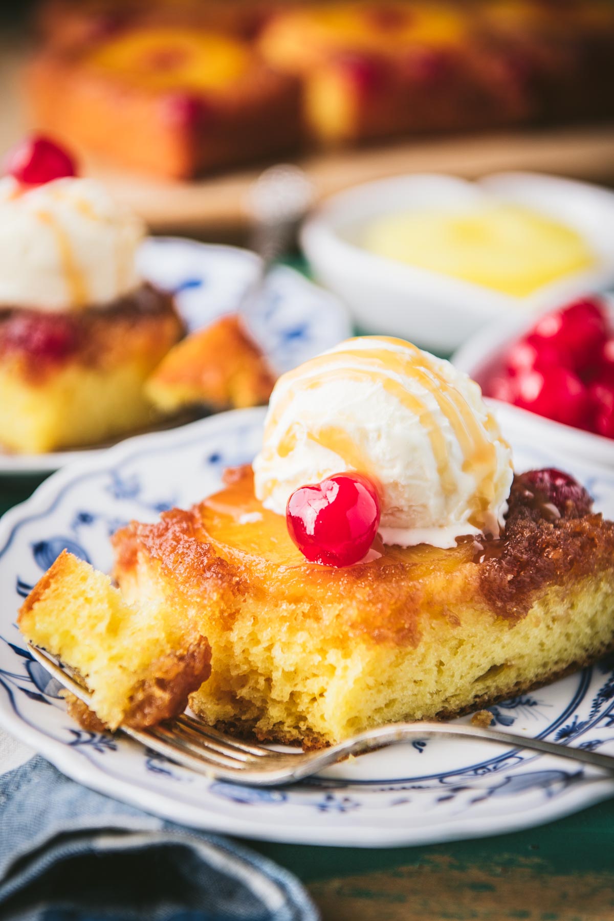 Close up side shot of a slice of easy pineapple upside down cake served on a plate with a scoop of vanilla ice cream