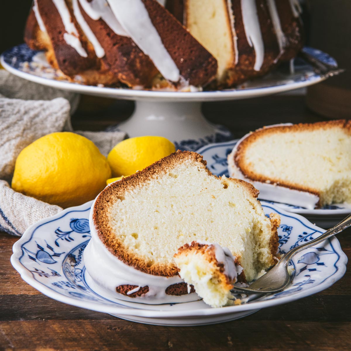 Square side shot of a slice of lemon pound cake on a blue and white plate with a fork.