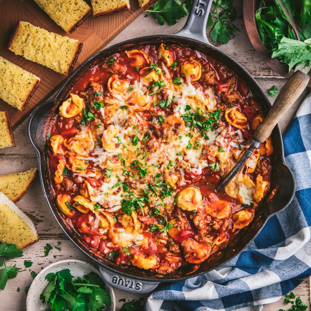 Square overhead image of sausage and cheese tortellini in a cast iron skillet.