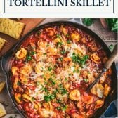 Overhead image of a skillet full of cheese tortellini with sausage and text title box at top