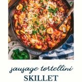 Overhead shot of Italian sausage and cheese tortellini in a skillet with text title at the bottom.