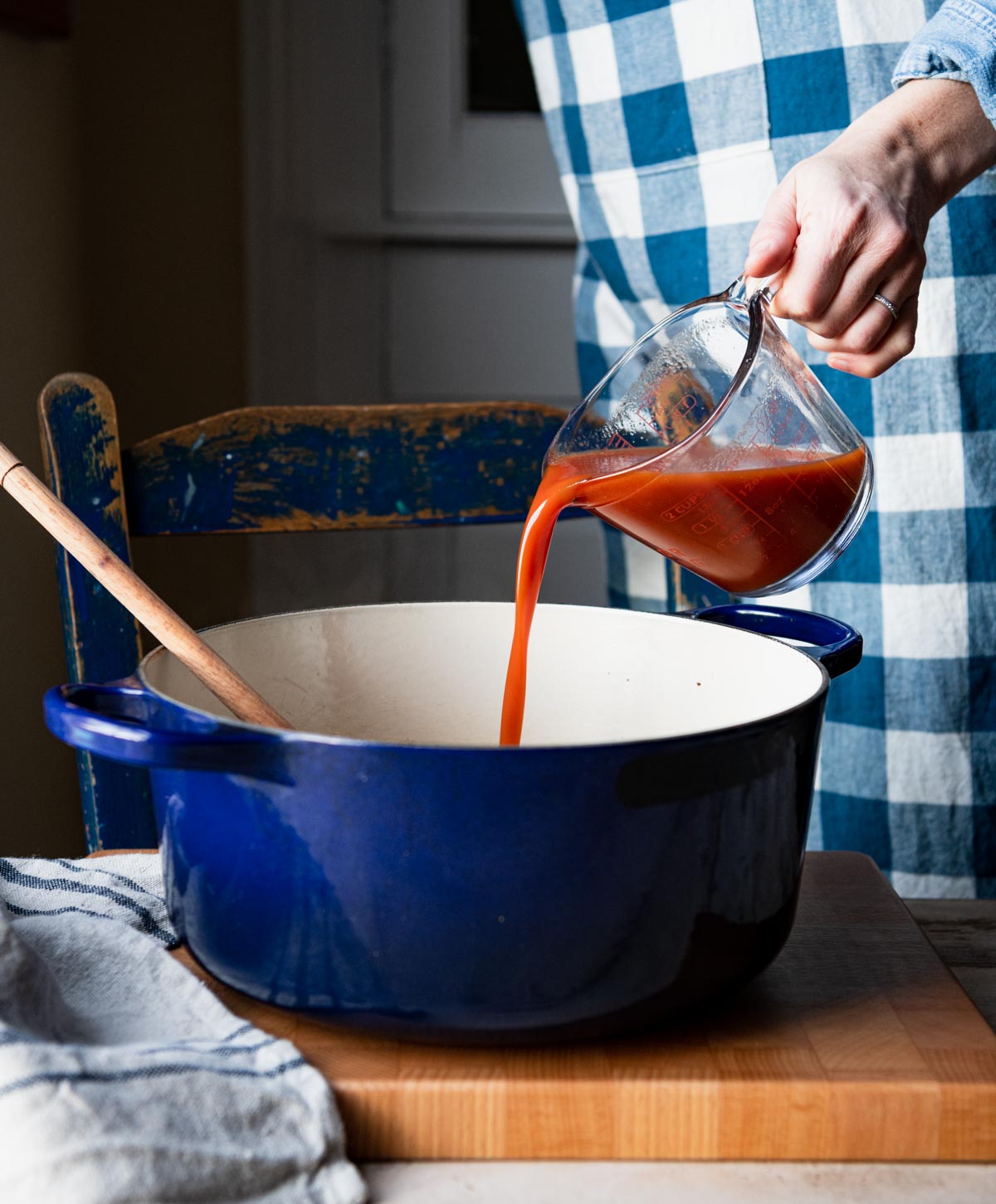 Pouring tomato juice into a Dutch oven