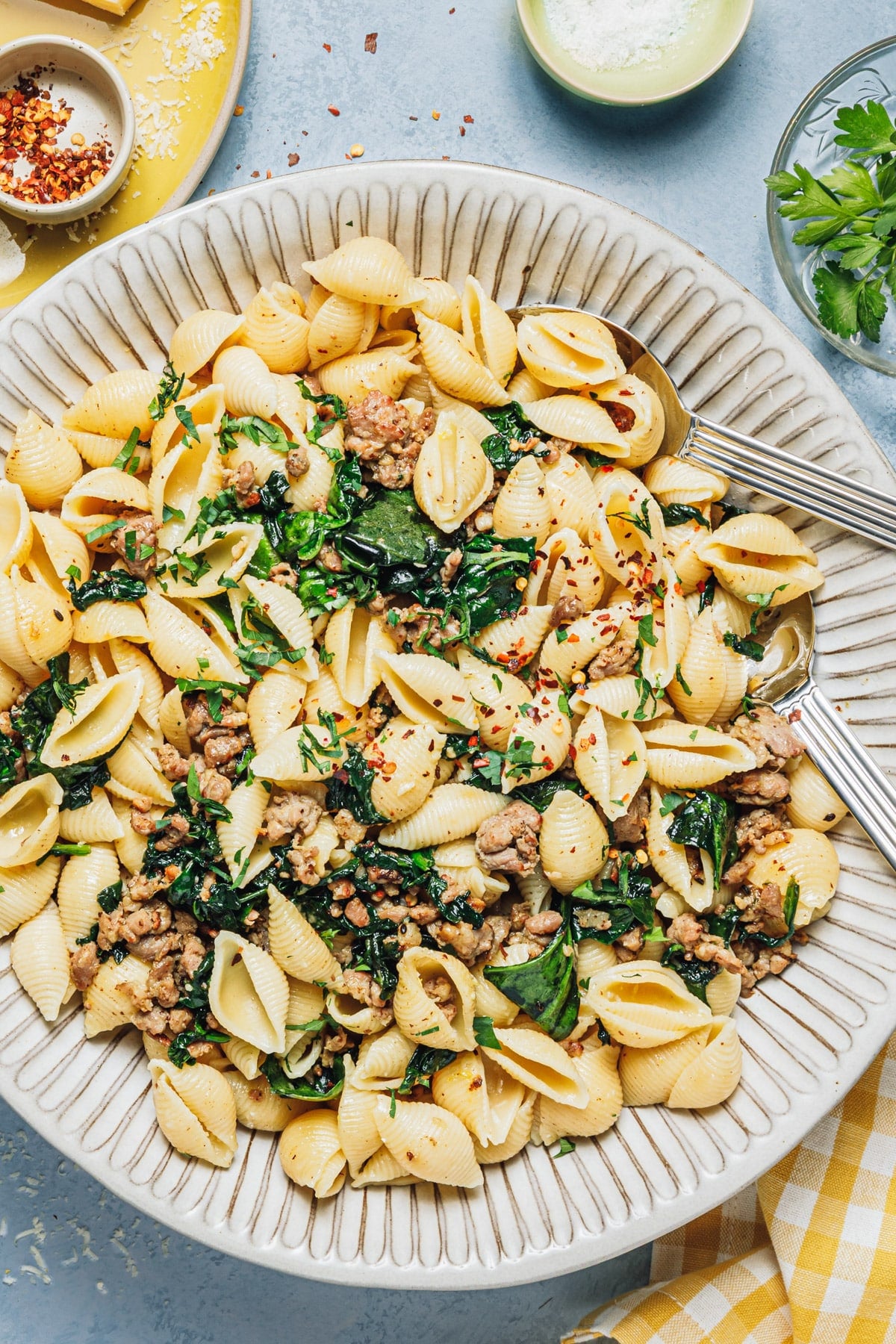 Serving bowl full of pasta with sausage and spinach.