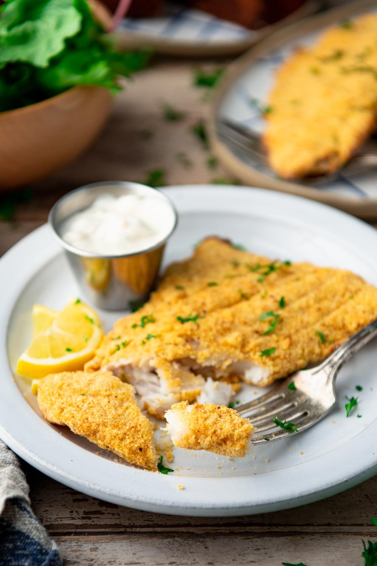 Close up shot of a bite of cornmeal crusted baked catfish on a fork.