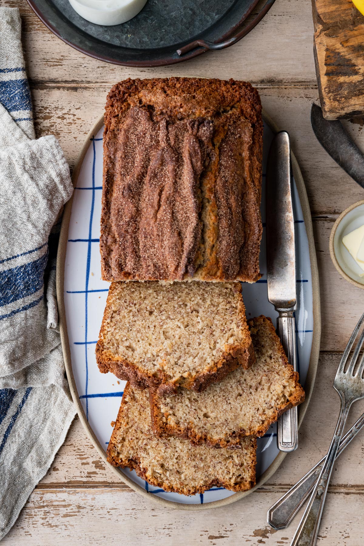 Overhead image of a sliced loaf of buttermilk banana bread on a rustic table.