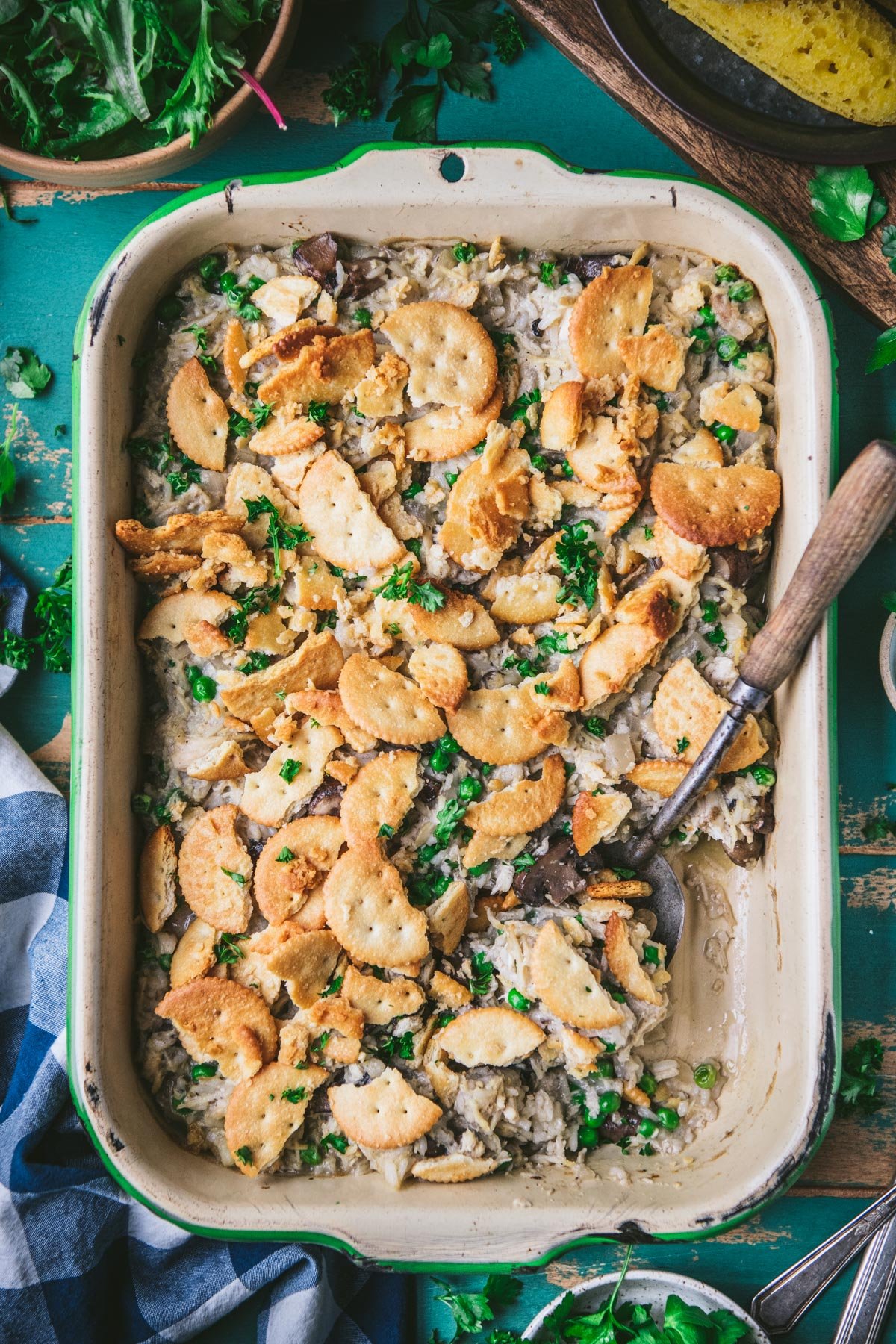 Overhead shot of a pan of chicken mushroom rice casserole on a turquoise vintage wooden table with side salad and cornbread