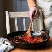 Sauteing tomato paste with shallots and garlic in a skillet.
