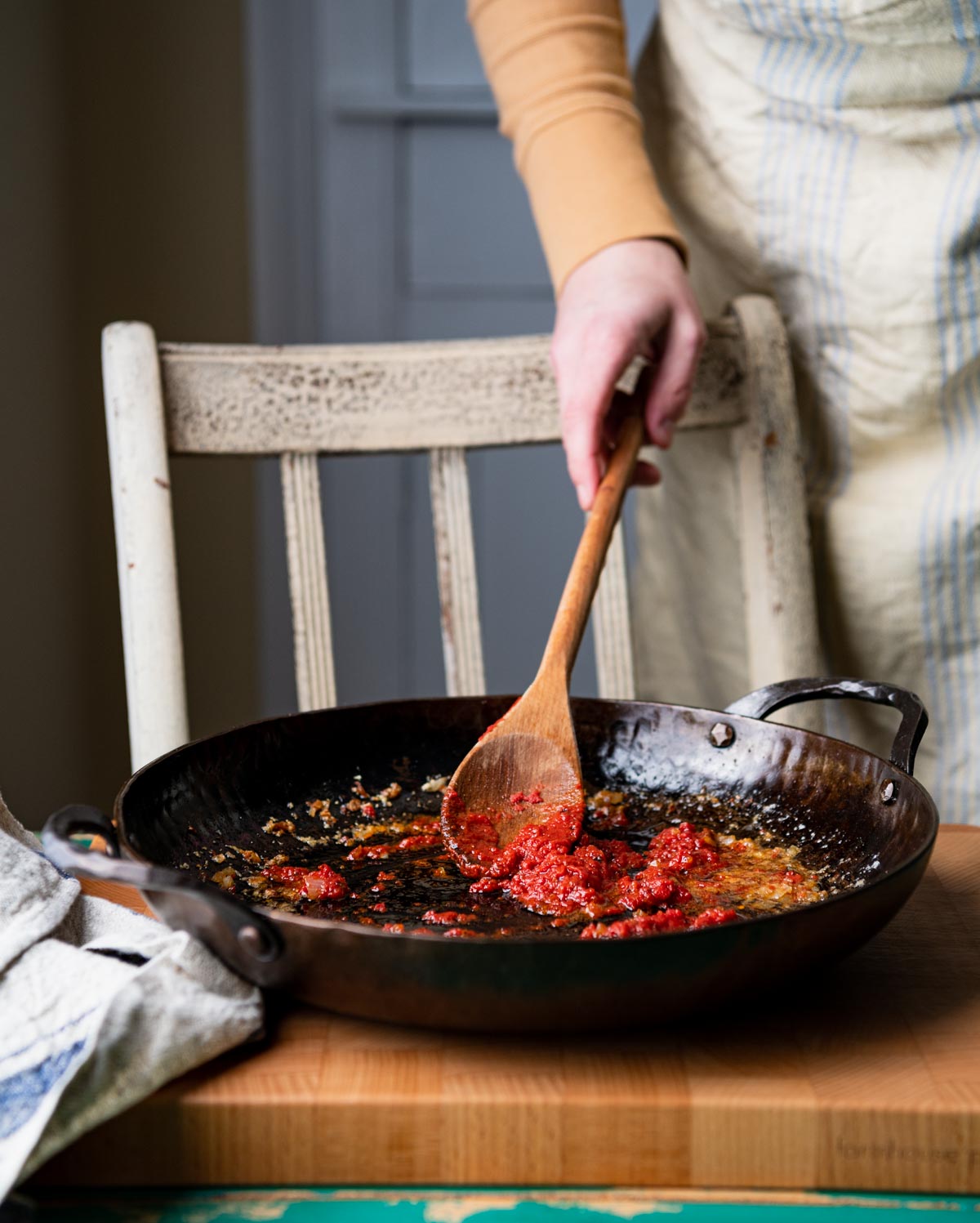 Sauteing tomato paste with shallots and garlic in a skillet.