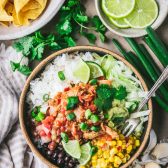 Chipotle chicken bowl with rice and toppings on a table.