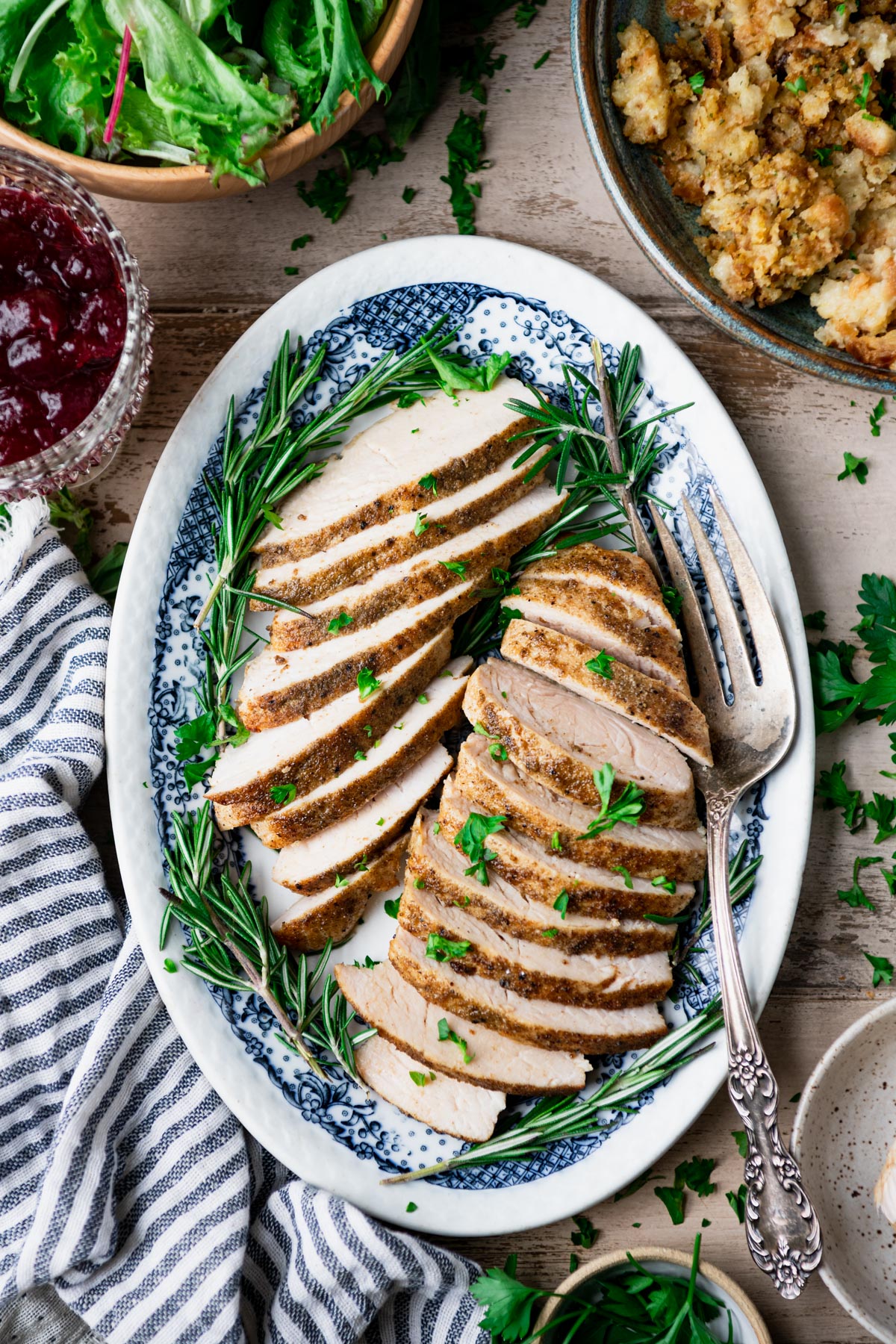 Overhead image of sliced crock pot turkey tenderloins on a blue and white platter.