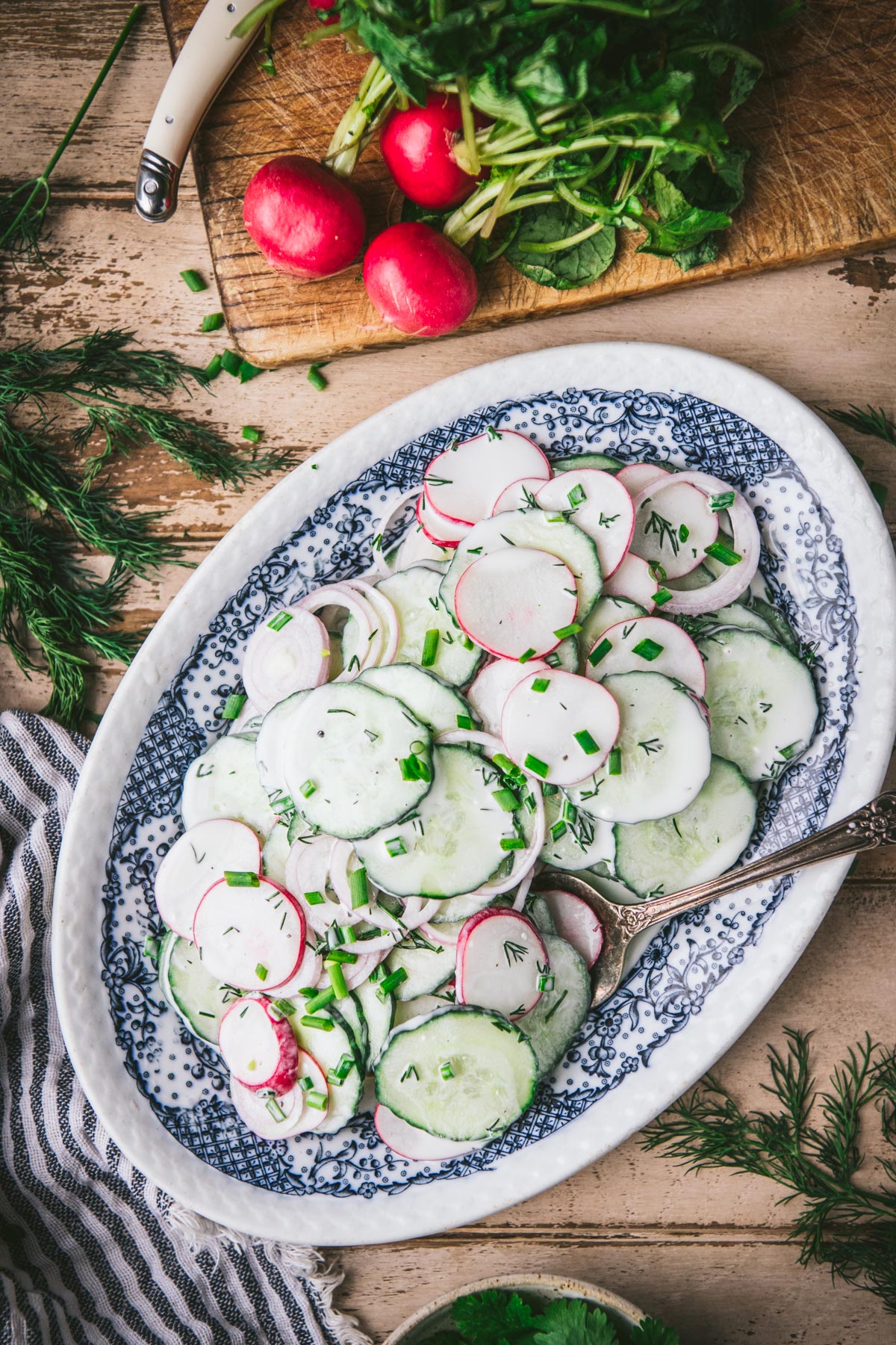 Overhead image of cucumber radish salad on a blue and white serving platter.