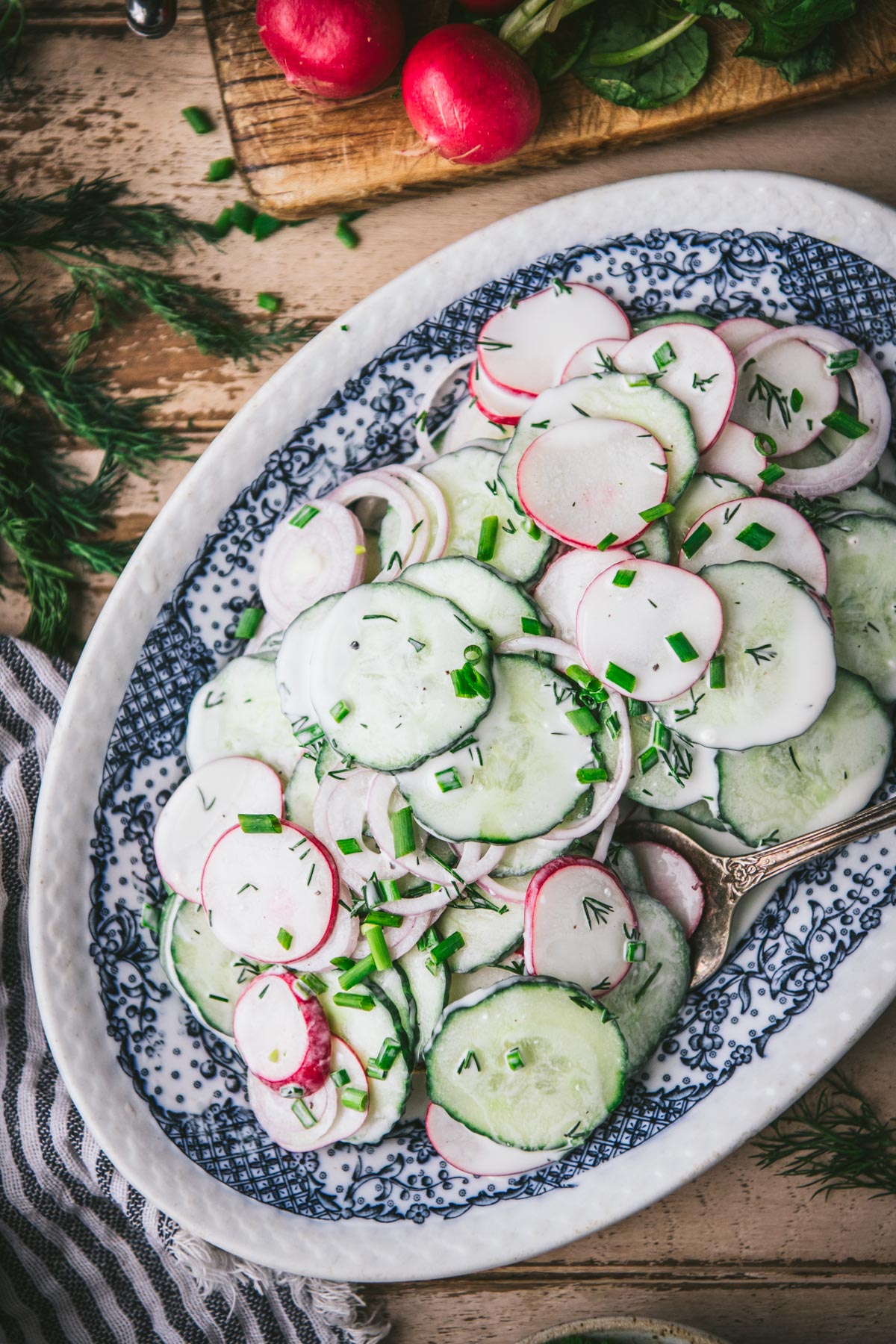 Close up shot of creamy cucumber radish dill salad on a wooden table.