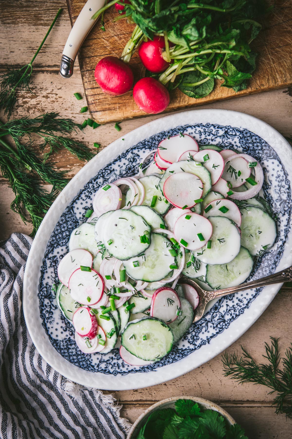 Overhead shot of creamy cucumber radish salad in a blue and white dish.